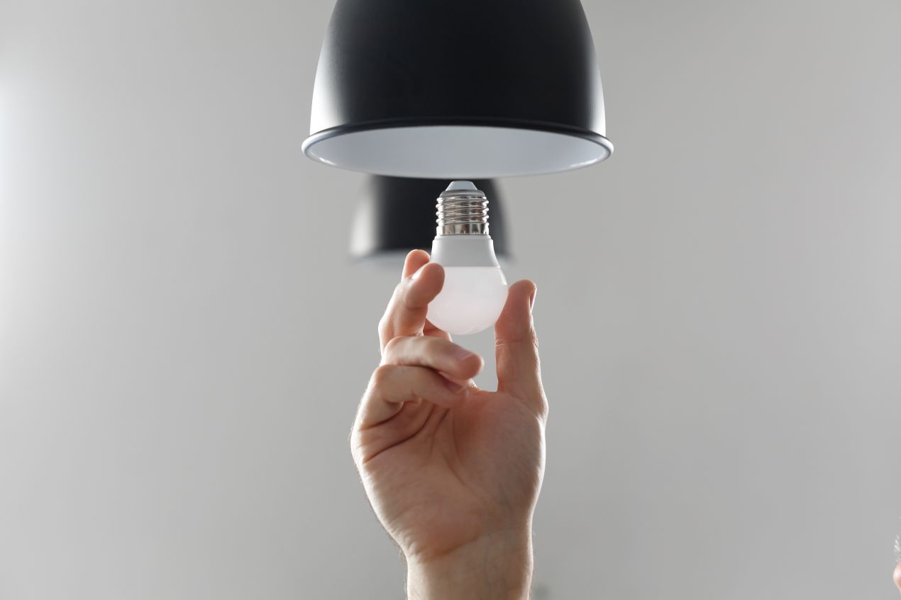 Hand setzt LED e27 Leuchtmittel in moderne schwarze Deckenleuchte ein