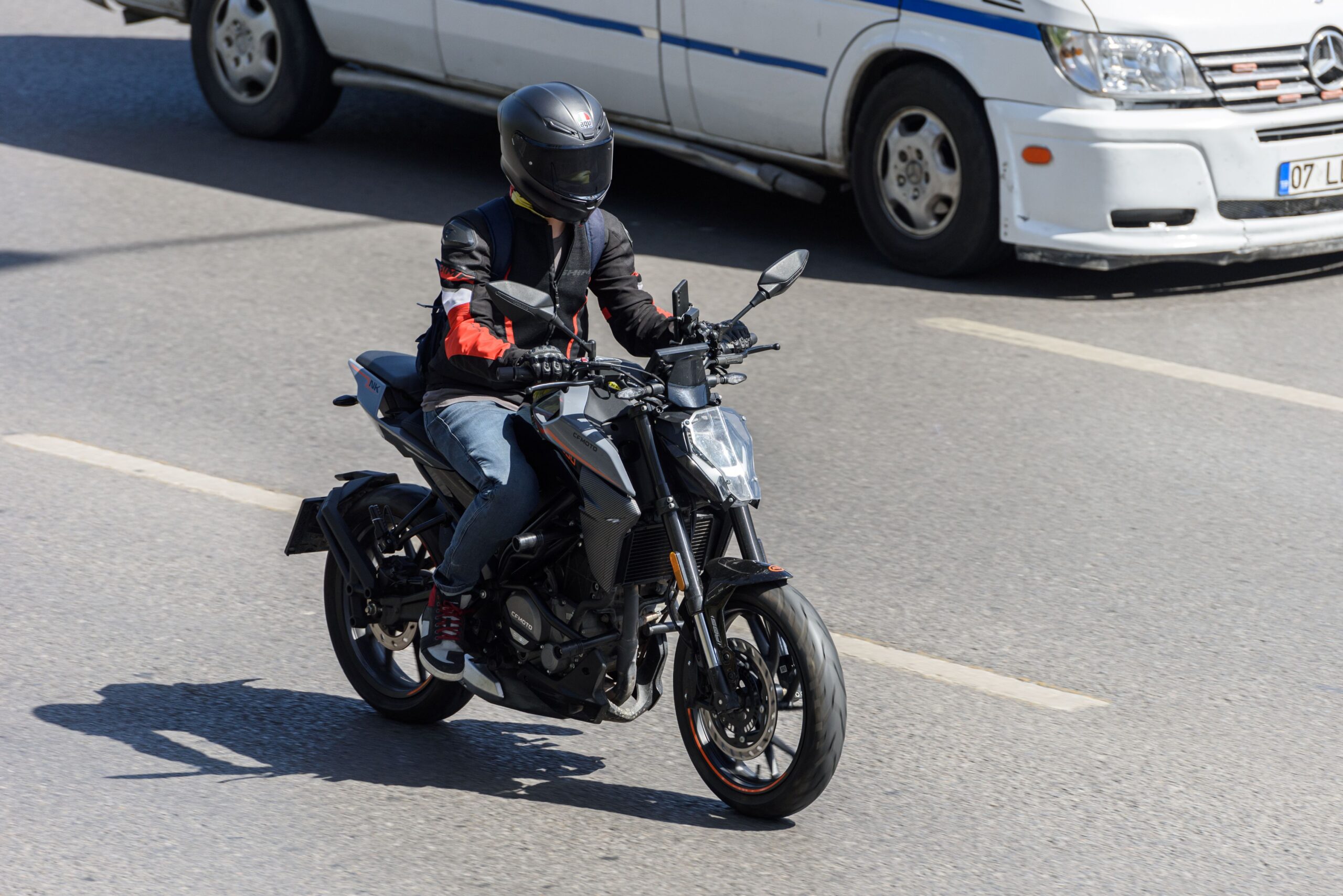 Motorradfahrer mit Schutzkleidung und schwarzem Helm auf Stadtstraße