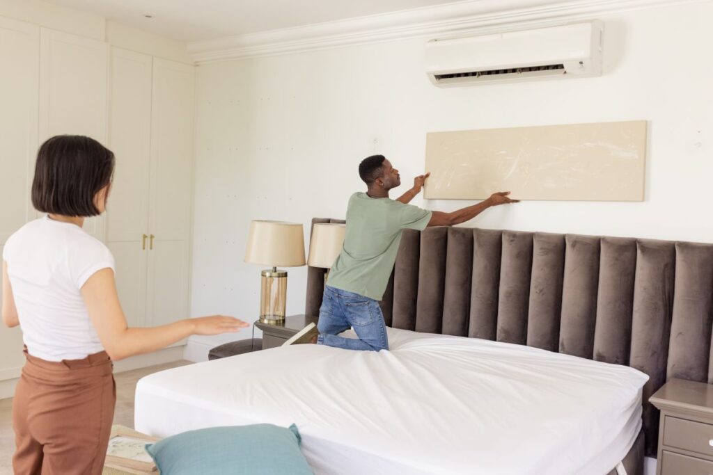 Paar bringt ein Akustikpaneel über dem Bett an, um die akustische Qualität und Atmosphäre im Schlafzimmer zu verbessern
